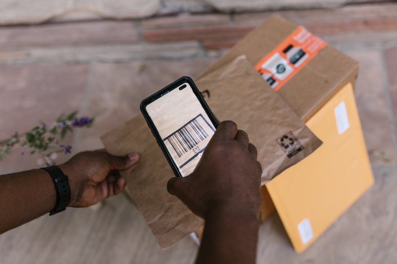 portfolio-05 A person scans package barcodes using a smartphone for delivery logistics.